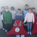 7 jeunes posent avec deux phryges, mascottes des JO d'été de Paris