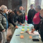 Les personnes, sur un stand de la Halle aux grains, remplissent des fiches-jeux