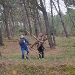 Deux jeunes portent des bout de bois pour construire une cabane