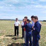 5 personnes autour d'un jeune qui pilote un drone avec une télécommande