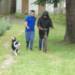 Un jeune homme court avec un chien en laisse, à ses côtés une personne sur un vélo avec un casque