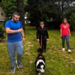 Un jeune homme avec un chien en laisse attaché à sa ceinture. A ses côtés, l'éducateur canin et son éducatrice spécialisée.