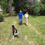 Un jeune homme avec un chien en laisse attaché à sa ceinture. A ses côtés, l'éducateur canin.