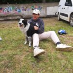 Un jeune homme assis sur le sol avec le chien noir et blanc.