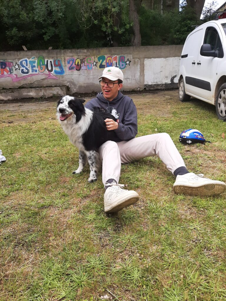 Un jeune homme assis sur le sol avec le chien noir et blanc.