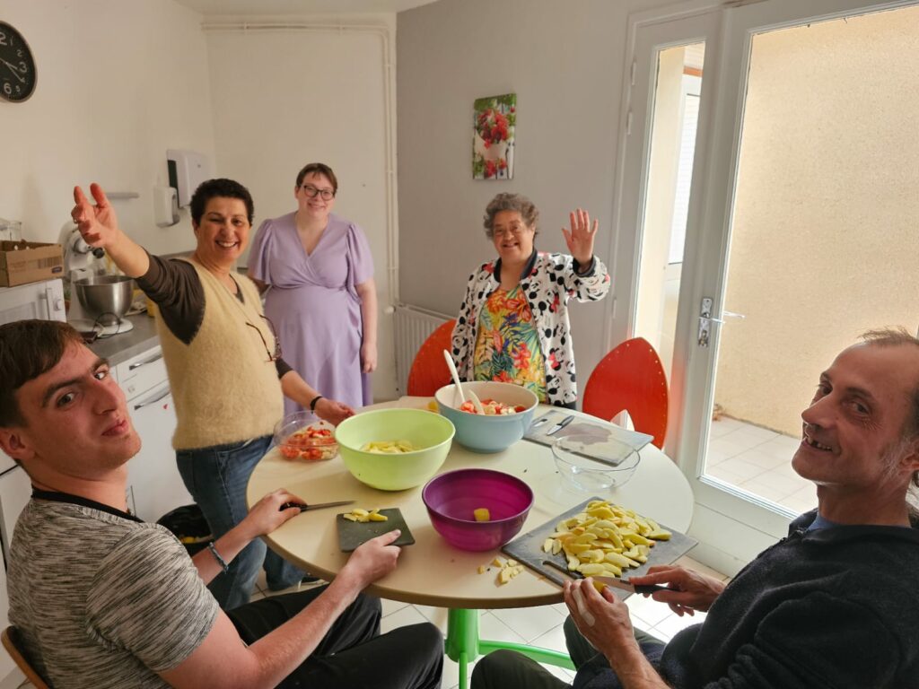 Autour de la table, résidents et accompagnants préparent la salade de fruits