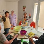 Autour de la table, résidents et accompagnants préparent la salade de fruits
