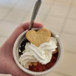Dans un ramequin, la salade de fruits avec de la chantilly et un biscuit en forme de cœur