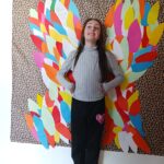 Une jeune fille pose devant les ailes déployées du papillon et semble prête à s'envoler