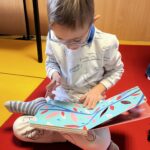 Un petit garçon assis sur un tapis rouge lit un livre