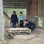 Deux jeunes et un accompagnant dans la nature, dans une maison en bois