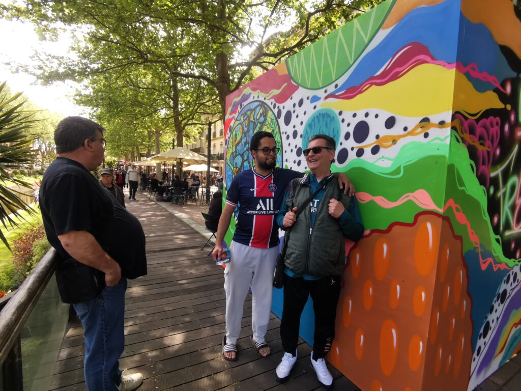 Trois personnes devant une fresque multicolore