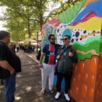 Trois personnes devant une fresque multicolore