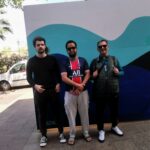 Trois résidents posent devant une fresque aux tons bleu