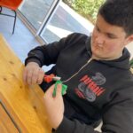 Un jeune homme confectionne une fleur pour le corso fleuri