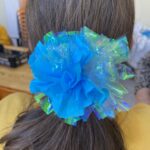 Une jeune fille de dos avec une des fleurs confectionnées dans les cheveux