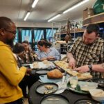 Dans l'épicerie de Marc, professionnels et personnes accompagnées du SAMSAH dégustent les fromages avec le patron de l'épicerie