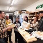 Dans l'épicerie de Marc, professionnels et personnes accompagnées du SAMSAH dégustent les fromages avec le patron de l'épicerie