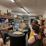Dans l'épicerie de Marc, professionnels et personnes accompagnées du SAMSAH dégustent les fromages avec le patron de l'épicerie