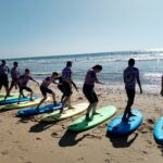 Les jeunes, debout sur leur planche face à l'océan
