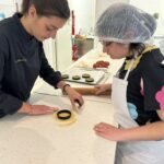 Elona et une jeune fille découpent la pâte avec un emporte-pièces