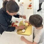 Elona et un jeune garçon remplissent un fond de tarte à la douille