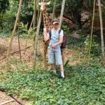 Un jeune à côté d'une fausse girafe