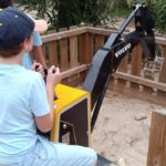 Un jeune s'amuse avec une pelle mécanique miniature