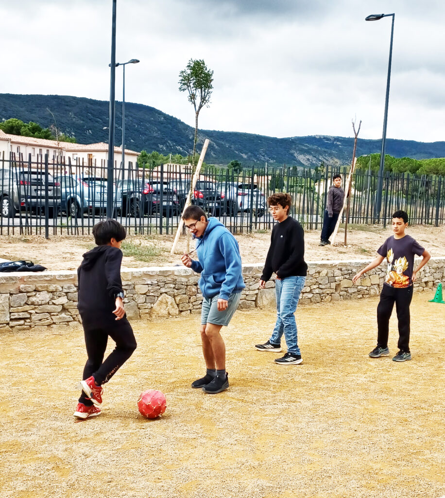 4 jeunes jouent au football dans la cour