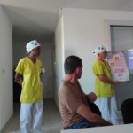 Une formatrice montre le schéma d'une dent, à ces côtés une autre formatrice et de dos un résident qui écoute attentivement