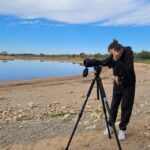 Un jeune regarde dans le grand objectif d'un appareil photo
