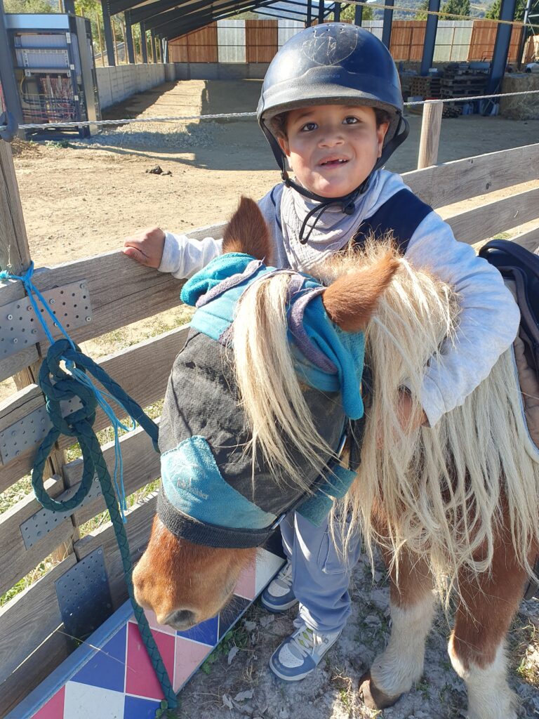 Un jeune accompagné enlace un poney