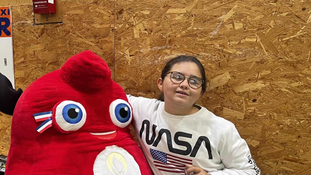 Une jeune fille pose avec la mascotte des JO de Paris