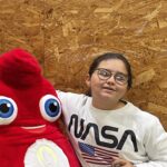 Une jeune fille pose avec la mascotte des JO de Paris