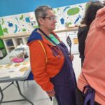 Une personne avec une spatule regarde les personnes qui cuisinent