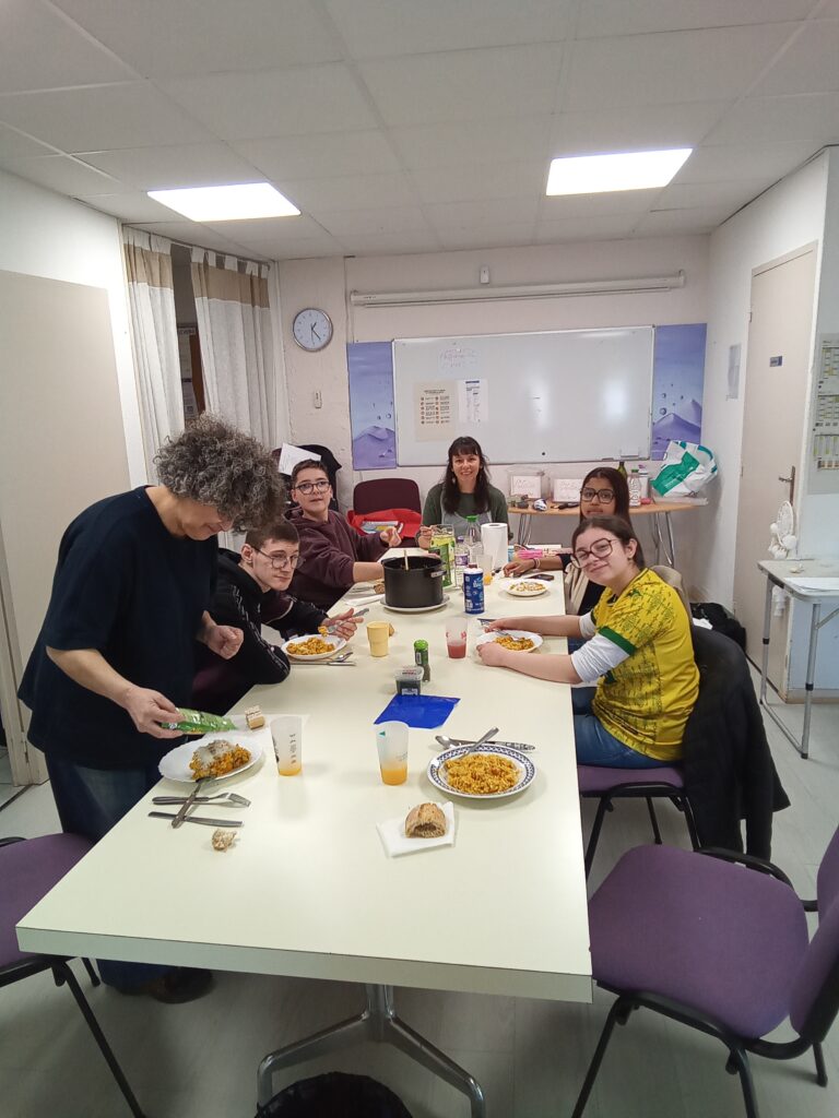 Les jeunes et des professionnels autour de la table partagent le repas préparé